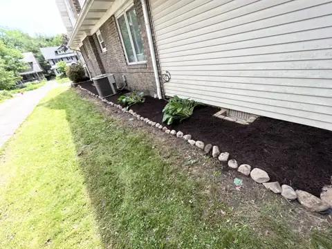 A cleared and mulched side bed beside the same home